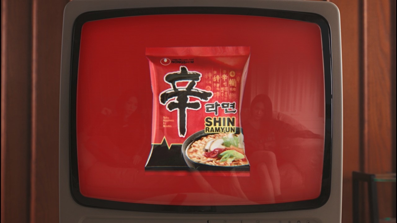 A Shin Ramyun pack on a red retro television screen, from the aespa campaign film