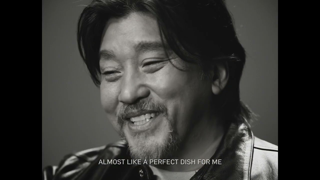 Chef Edward Lee smiling in a black-and-white close-up from the Shin Toomba commercial